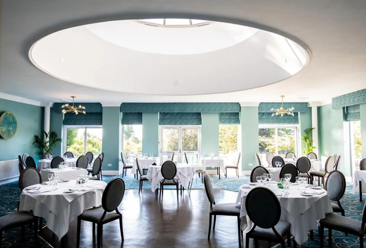 a dining room with tables and chairs and a large ceiling at Manor Parc Hotel in Cardiff