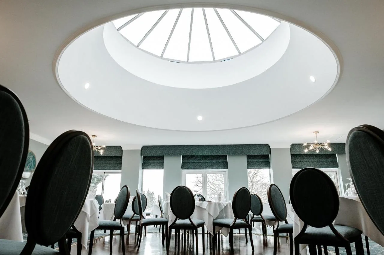 a dining room with a large skylight and tables and chairs at Manor Parc Hotel in Cardiff