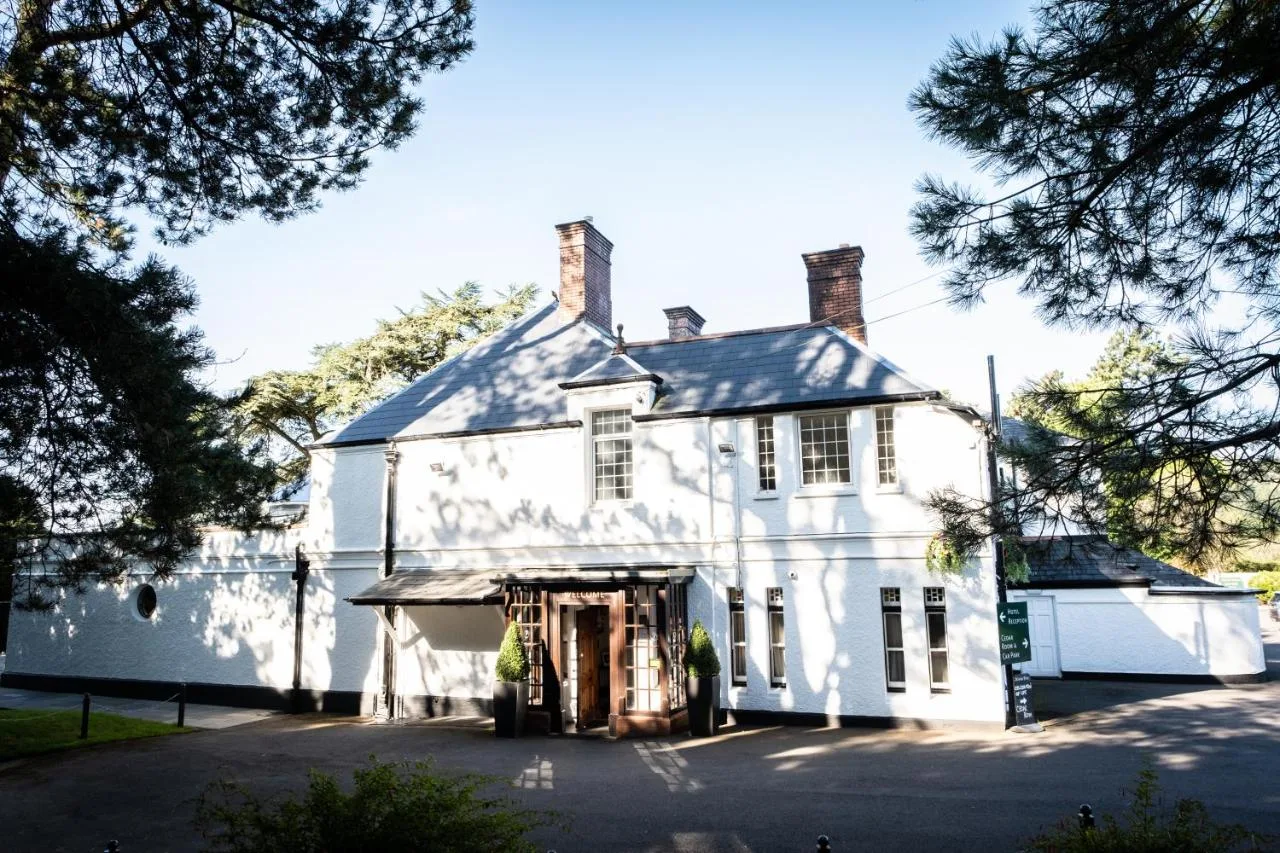 a large white house with a large garage at Manor Parc Hotel in Cardiff