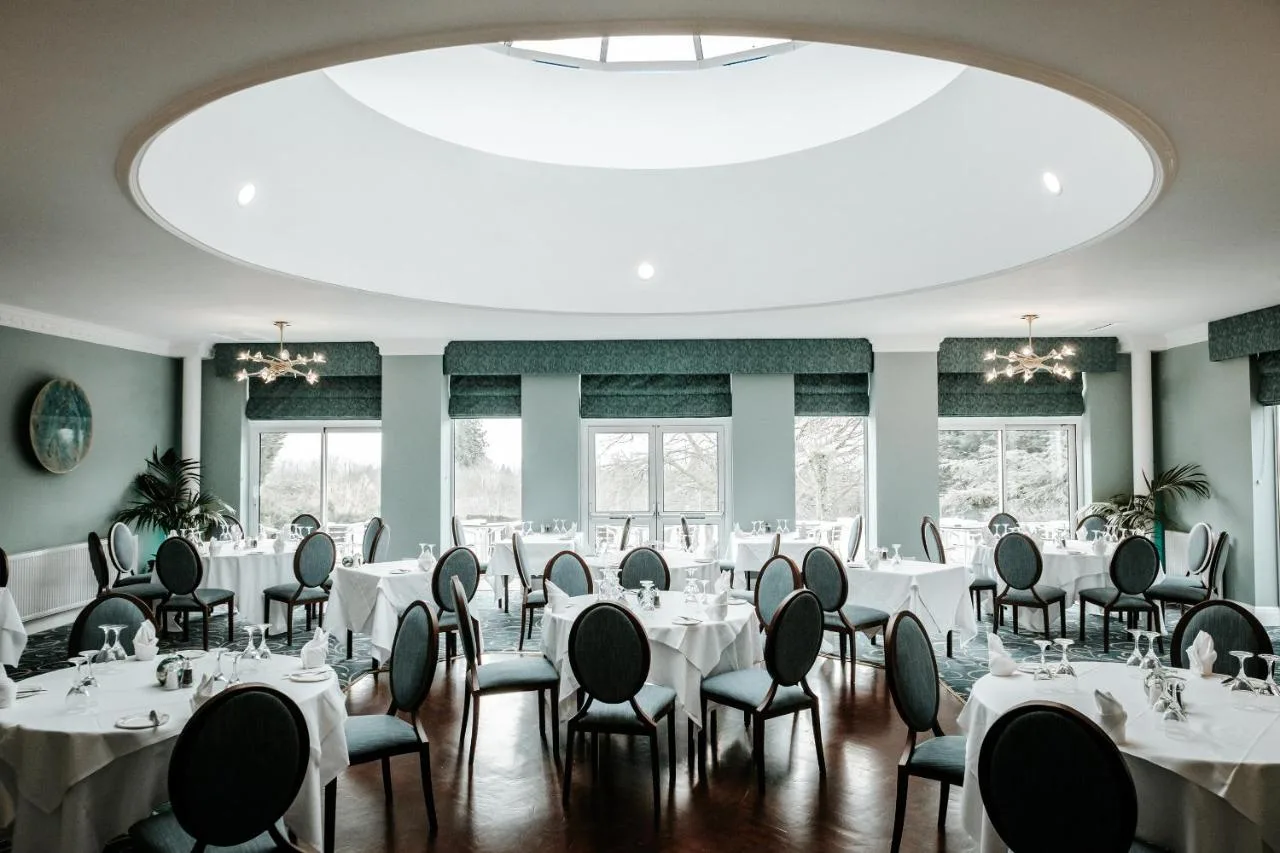 a room with tables and chairs and a large ceiling at Manor Parc Hotel in Cardiff